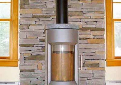 Wood Stove and Chimney Installation with Cultured Stacked Stone - The stove is tall, round and modern windows on both sides of hearth